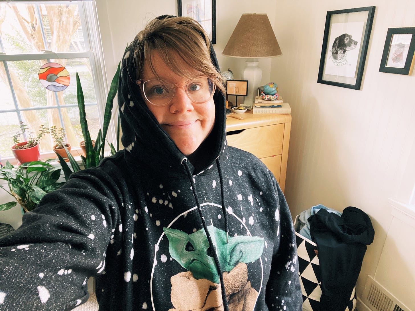 A selfie of a person with dishevled blonde hair wearing a hooded sweatshirt. The sweatshirt has an image of Baby Yoda on it.