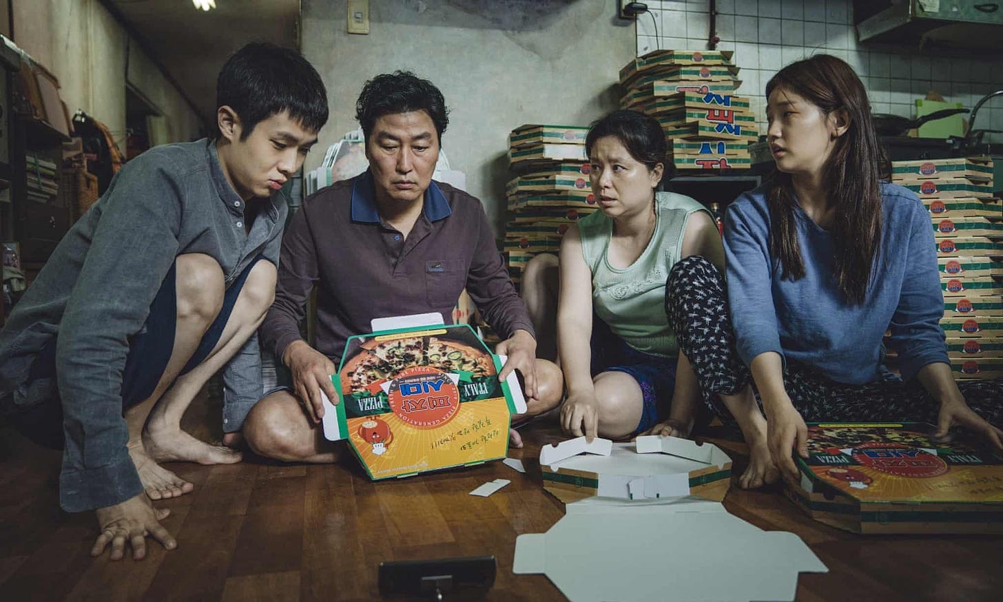 The Kim Family fold pizza boxes in a still from early on in the film Parasite.