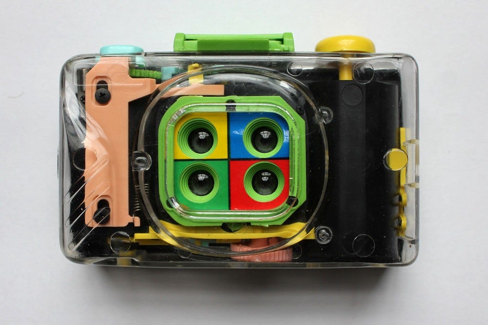 Clear plastic camera with four lenses, each surrounded by a different color.