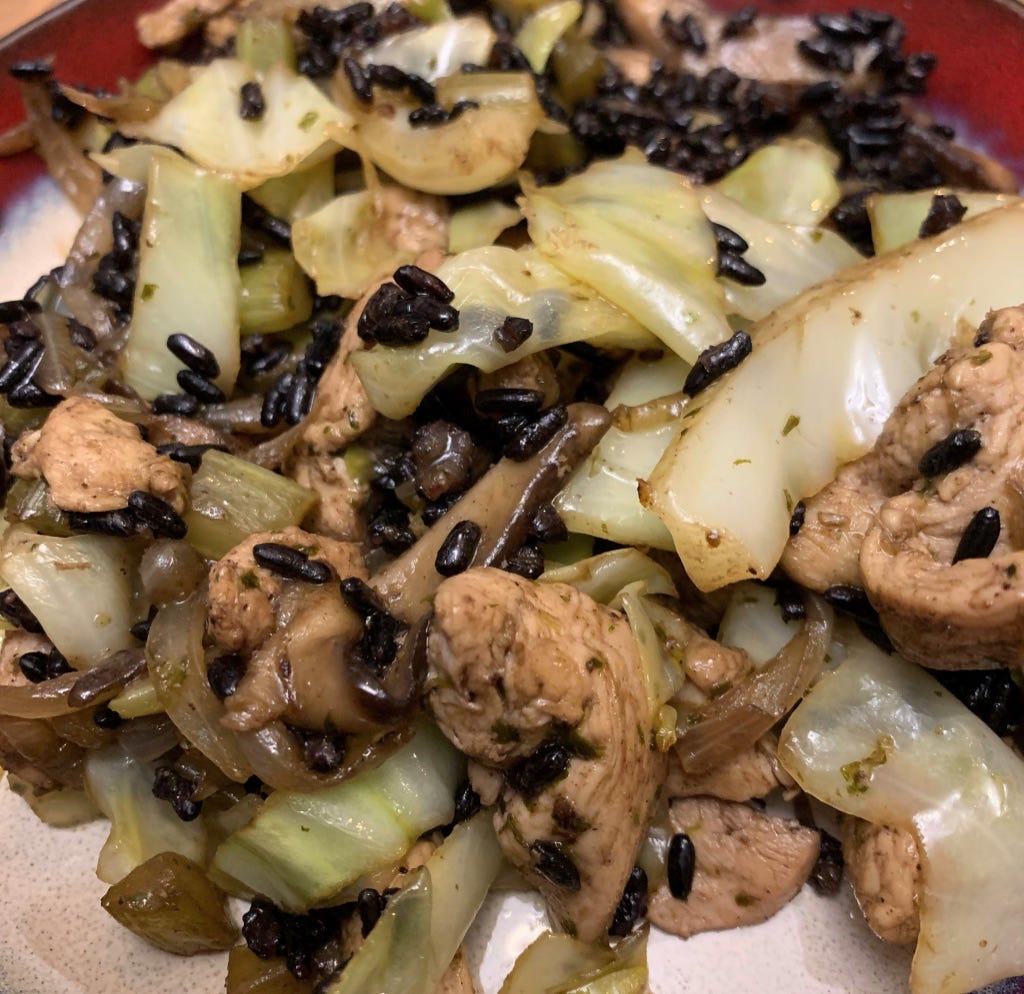 Photo is a plate of stir-fried chicken, with cabbage and black rice