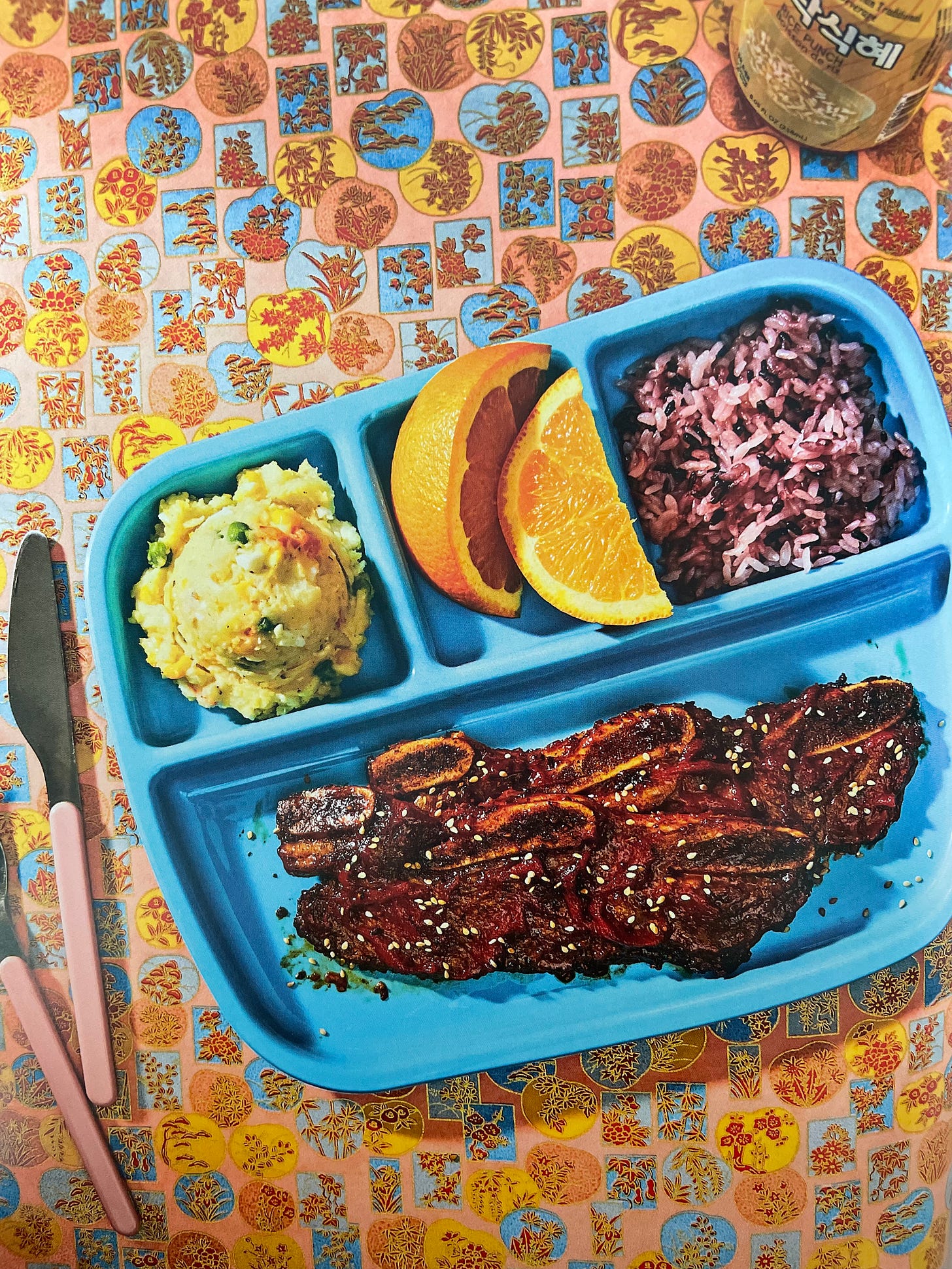 LA style kalbi on a school lunch tray with a scoop of potato salad, orange slices, and rice