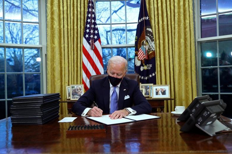 President Joe Biden signs executive orders in the Oval Office, January 20, 2021. The military flags displayed during the Donald Trump presidency have been replaced by just an American flag and one with the Presidential Seal, and a collection of family photos.

REUTERS/Tom Brenner