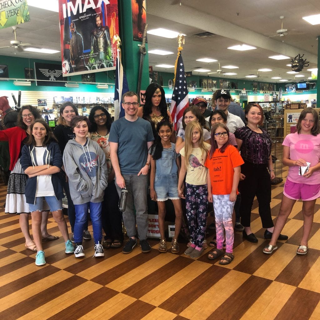 Image shows a class of ABC students and their volunteer standing together in a comic book store.