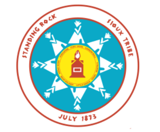the badge of the standing rock sioux tribe. a red circle with "standing rock sioux tribe july 1873" written on it, and a circle within that of 8 tepees and 