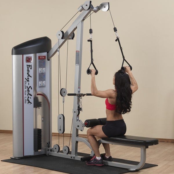 Woman seated on a weight machine performs the lat pulldown exercise.