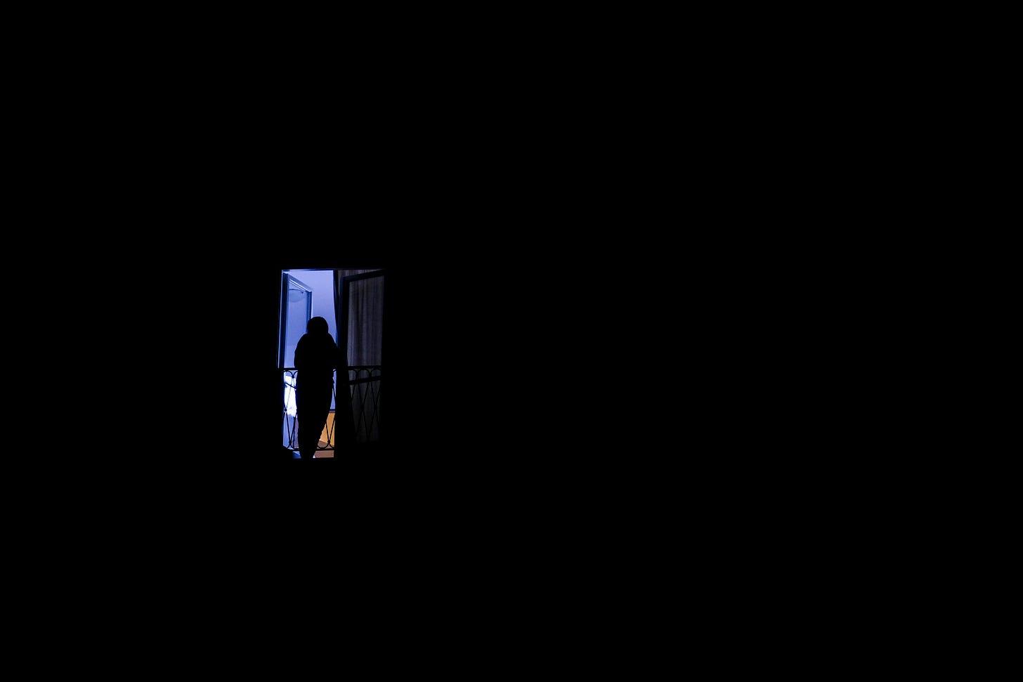 Silhoutteof a person on a small balcony in darkness