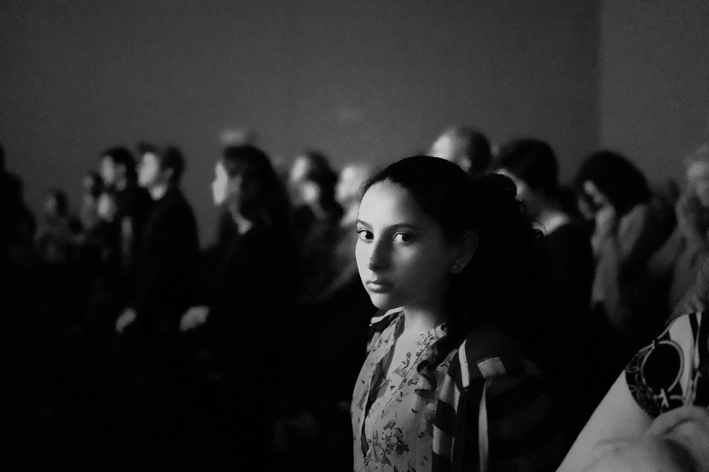 black and white image of a girl in a crowd looking at the camera for article by Larry G. Maguire
