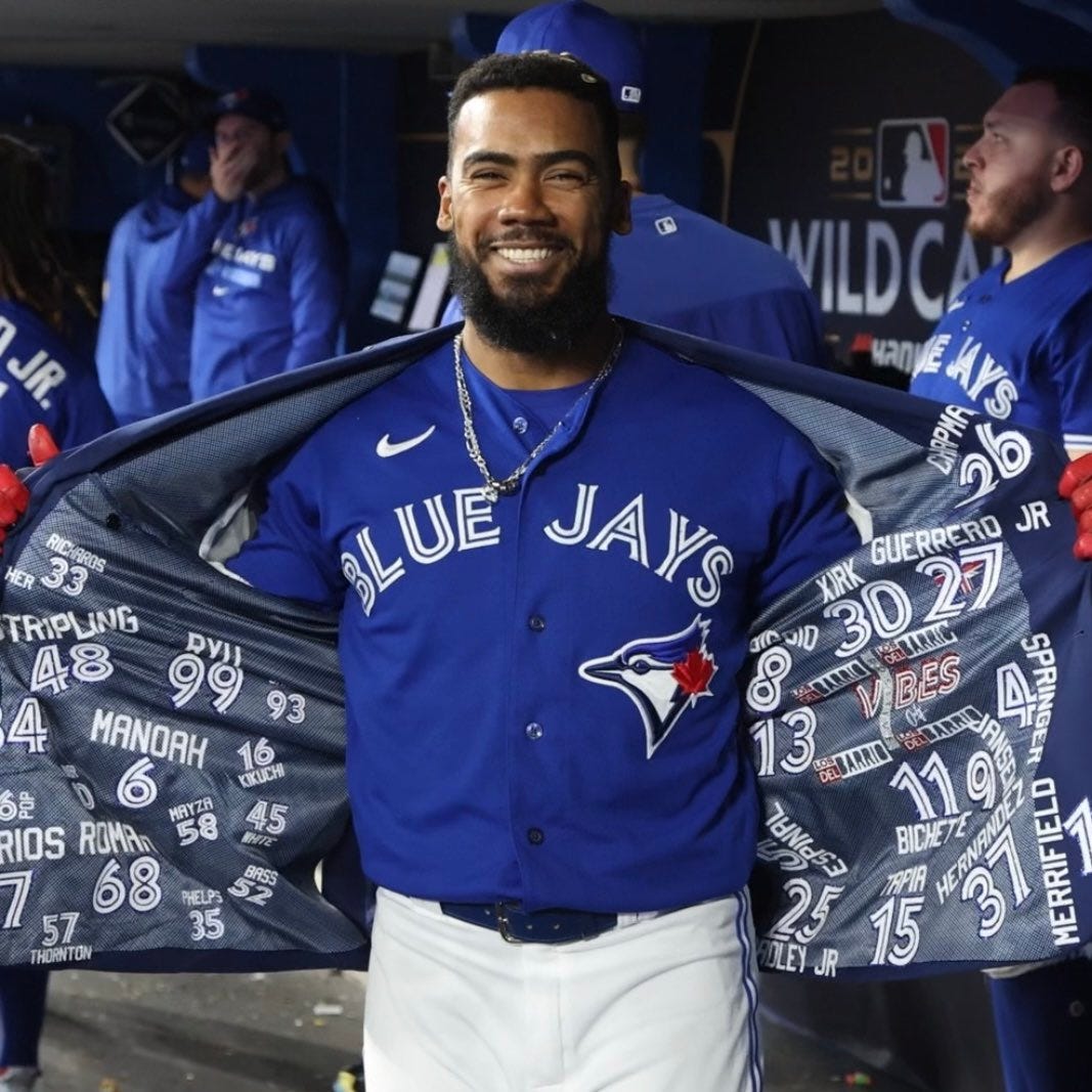 Teoscar Hernández smiles as he shows off the Blue Jays' playoff Home Run Jacket.