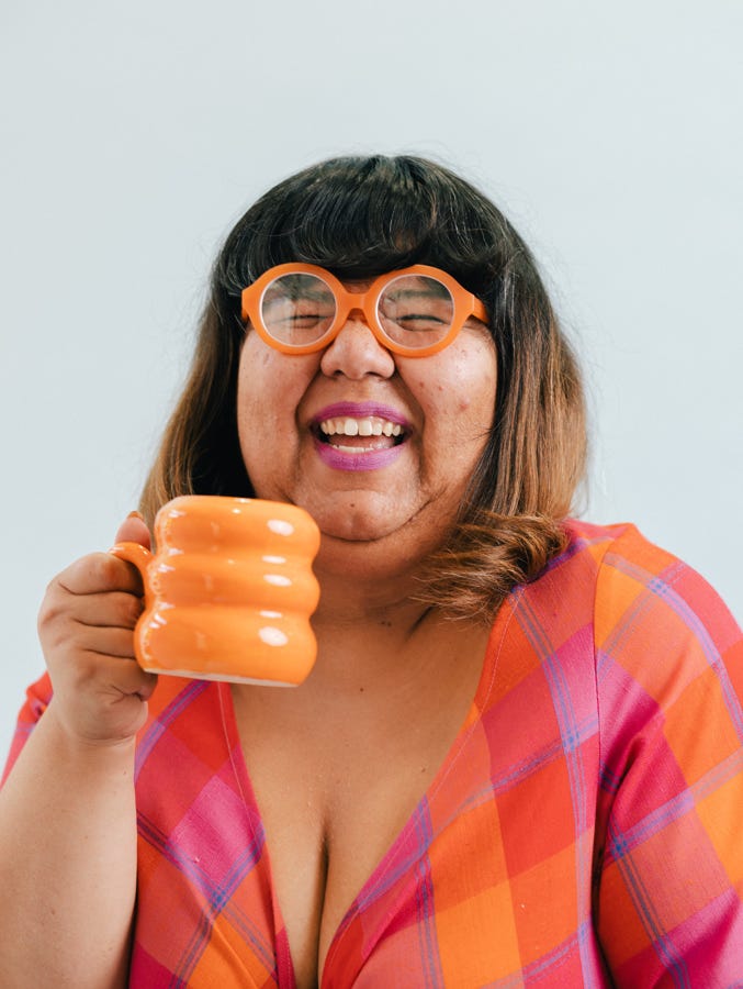 Headshot of today's guest, Virgie Tovar, smiling with a mug in her hand