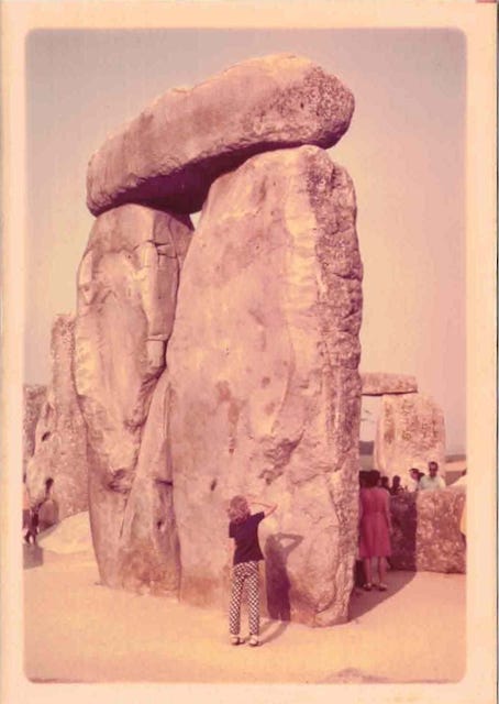 A young girl with her back to the camera, looks up at part of the Stonehenge monument in England.