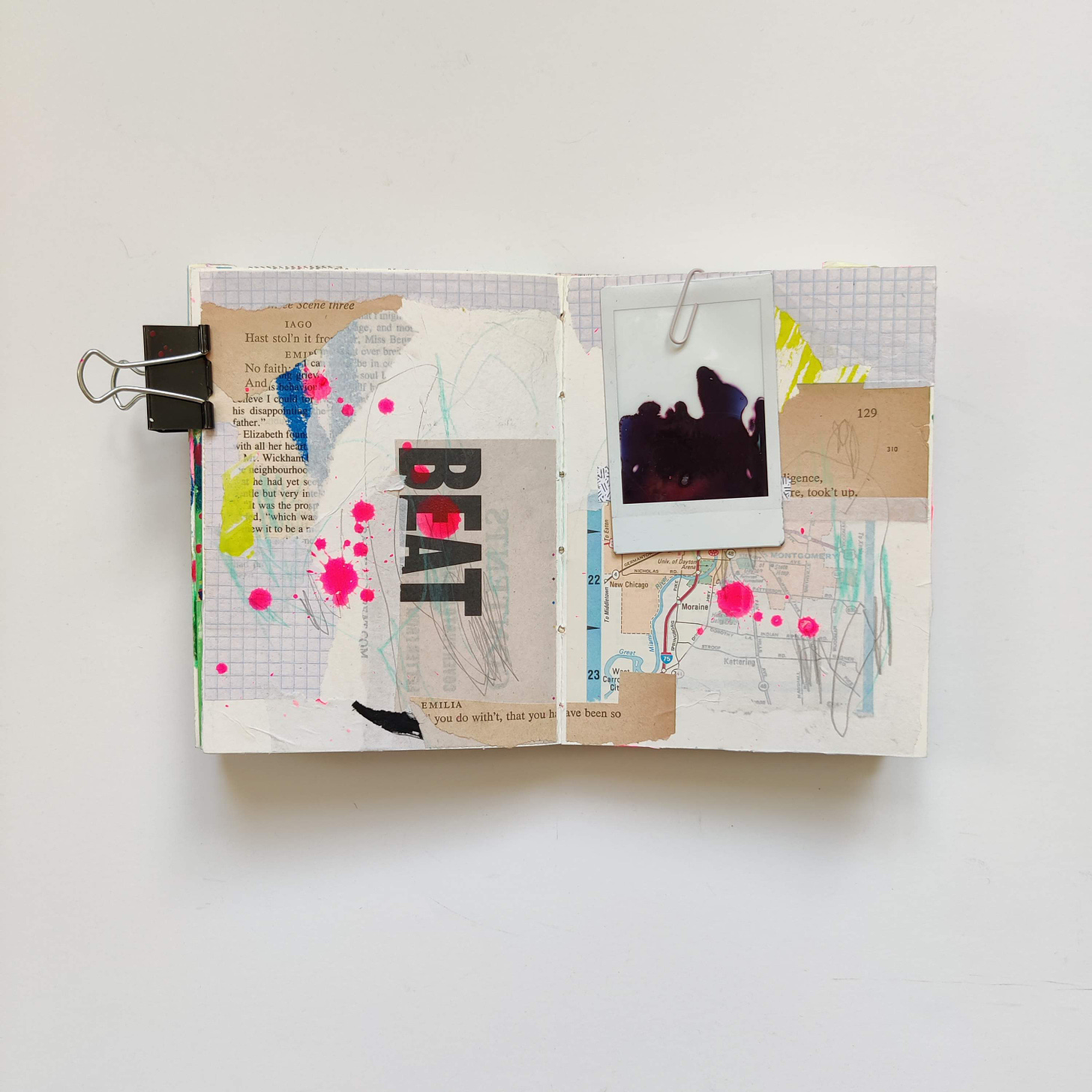 An open mixed media art journal with a layer of geometric and text-based collage, splatters of neon pink and a found mis-developed Instax photo.