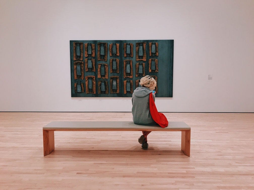 person sitting on a bench in art gallery, facing the painting