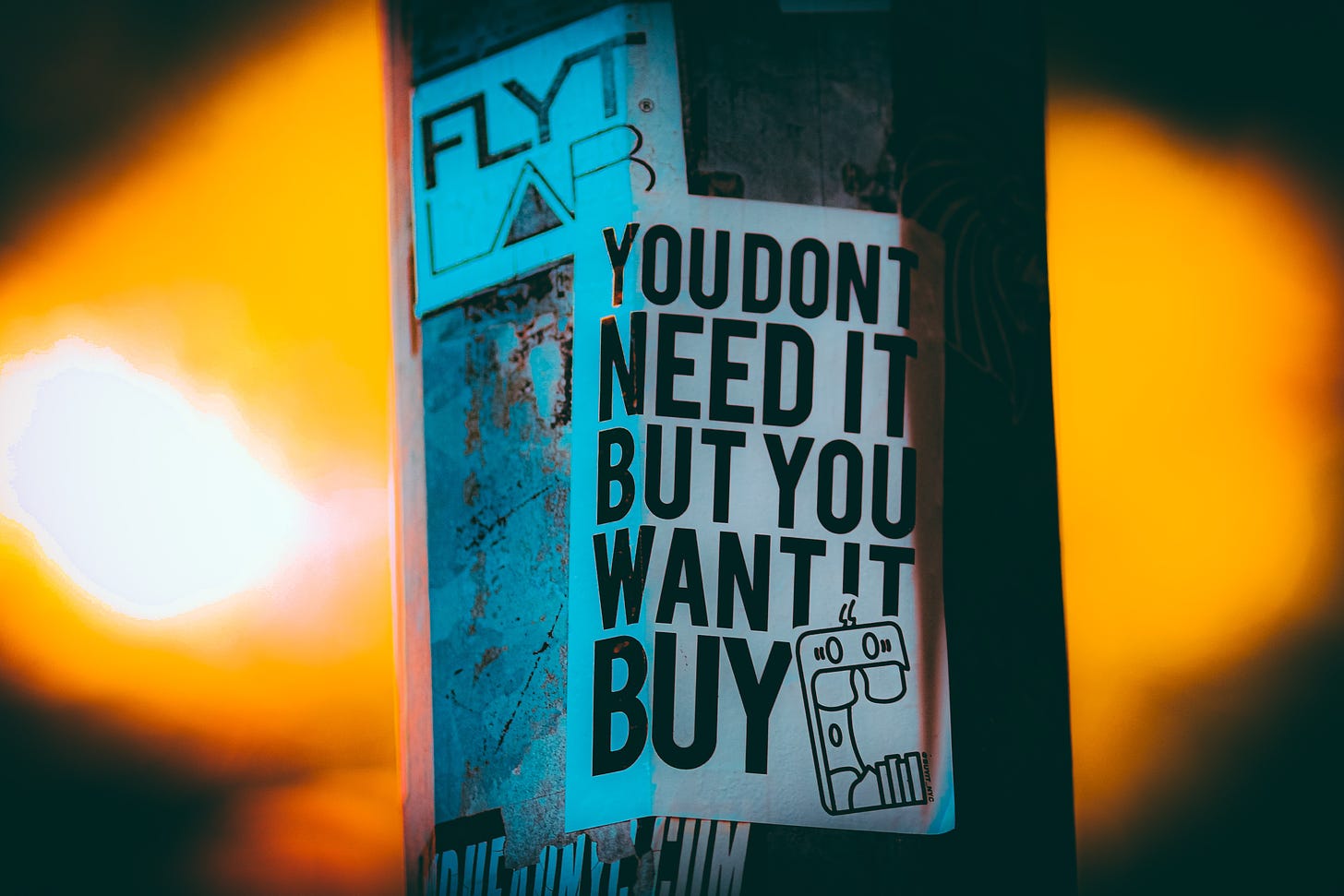 A flyer is stuck to a post "You don't need it, but you want it. Buy"