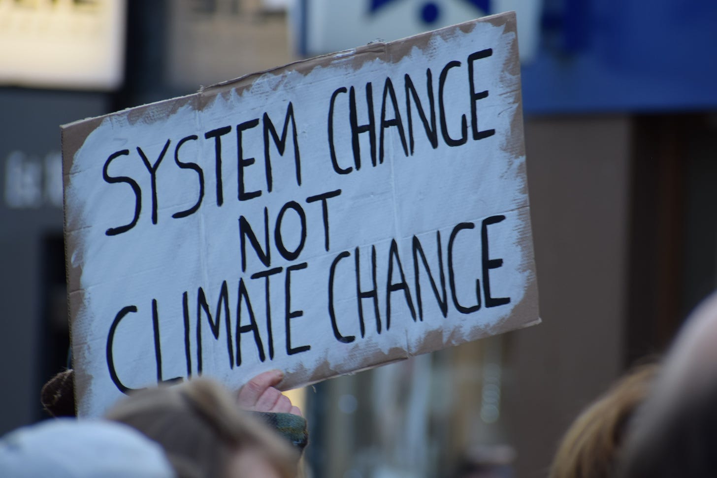 A protest sign reading "System Change Not Climate Change"