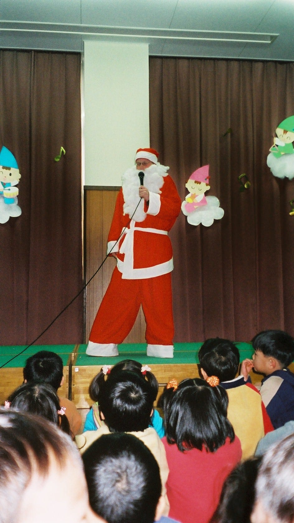 An image of the author dressed as Santa Claus, standing on a stage, with a microphone.