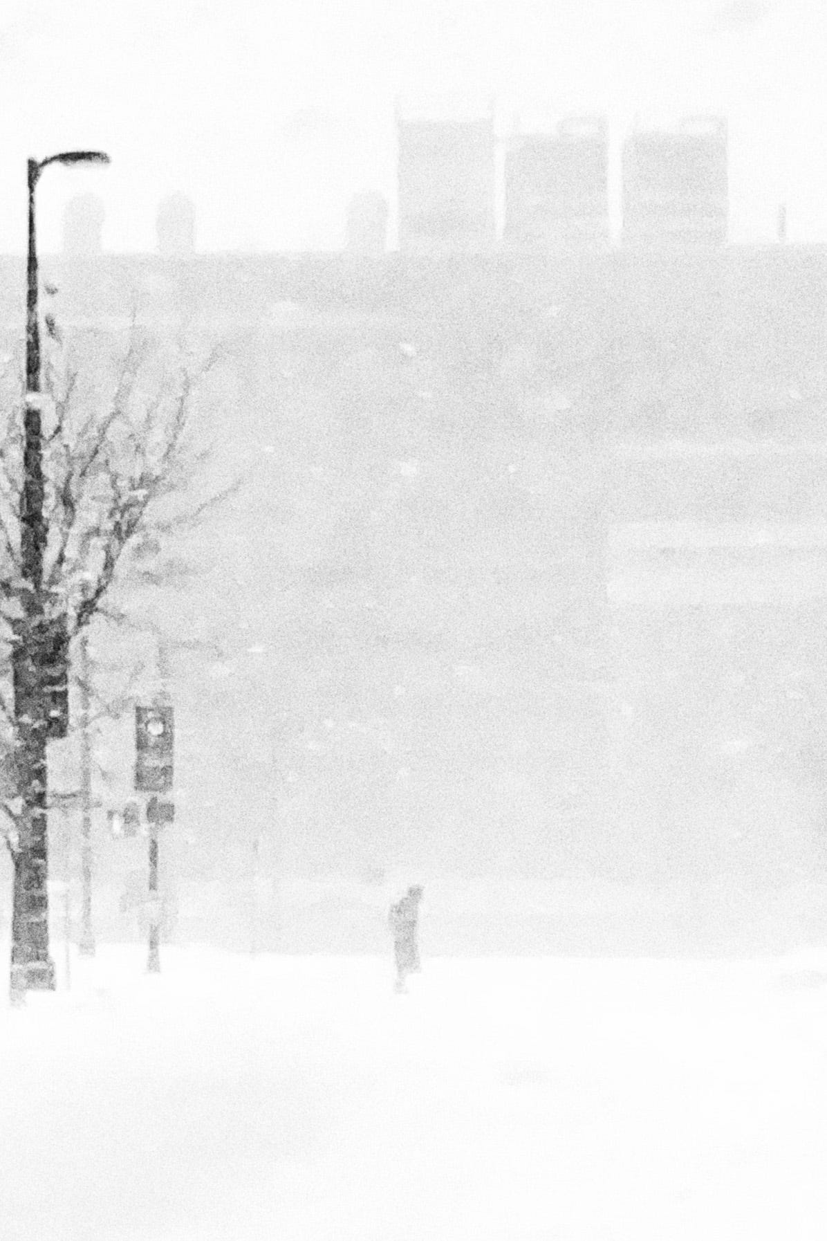 A person in the distance crosses the street in blizzard conditions.