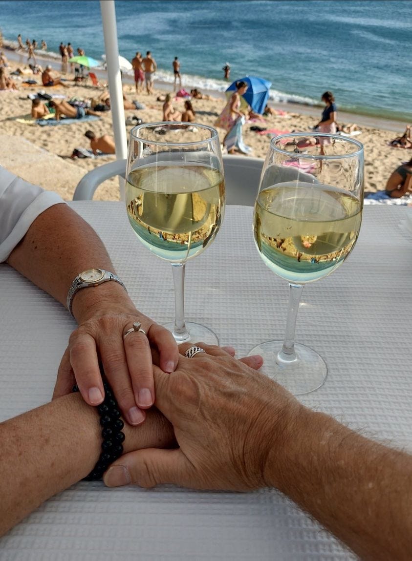 Holding hands with wine glasses on a beach