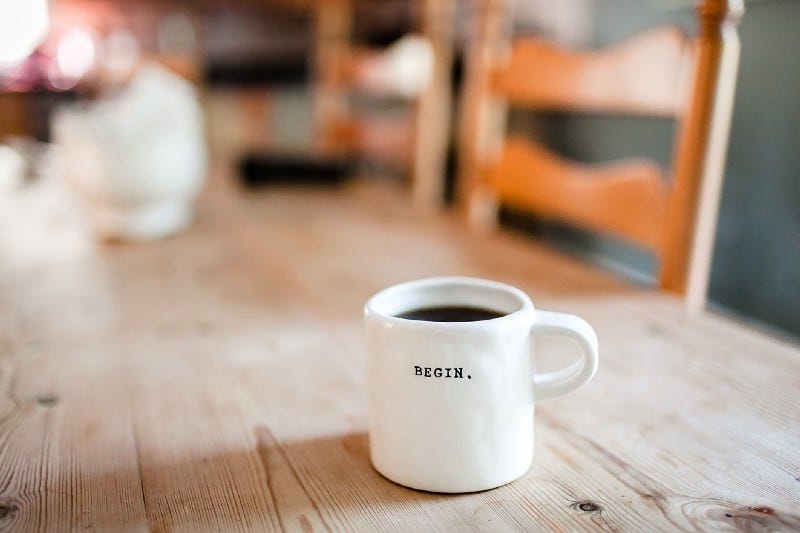 image of a white coffee mug with the word begin written on it, on a table