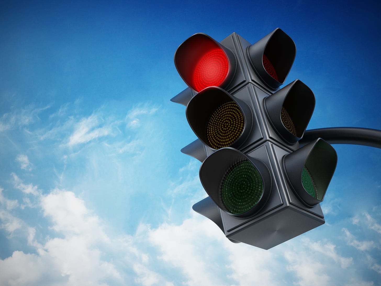 A red traffic light against a blue sky