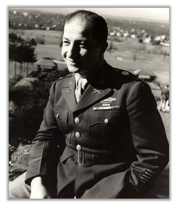 Dervishian poses casually, with one hand in his pocket. He is in uniform and smiling at the camera.
