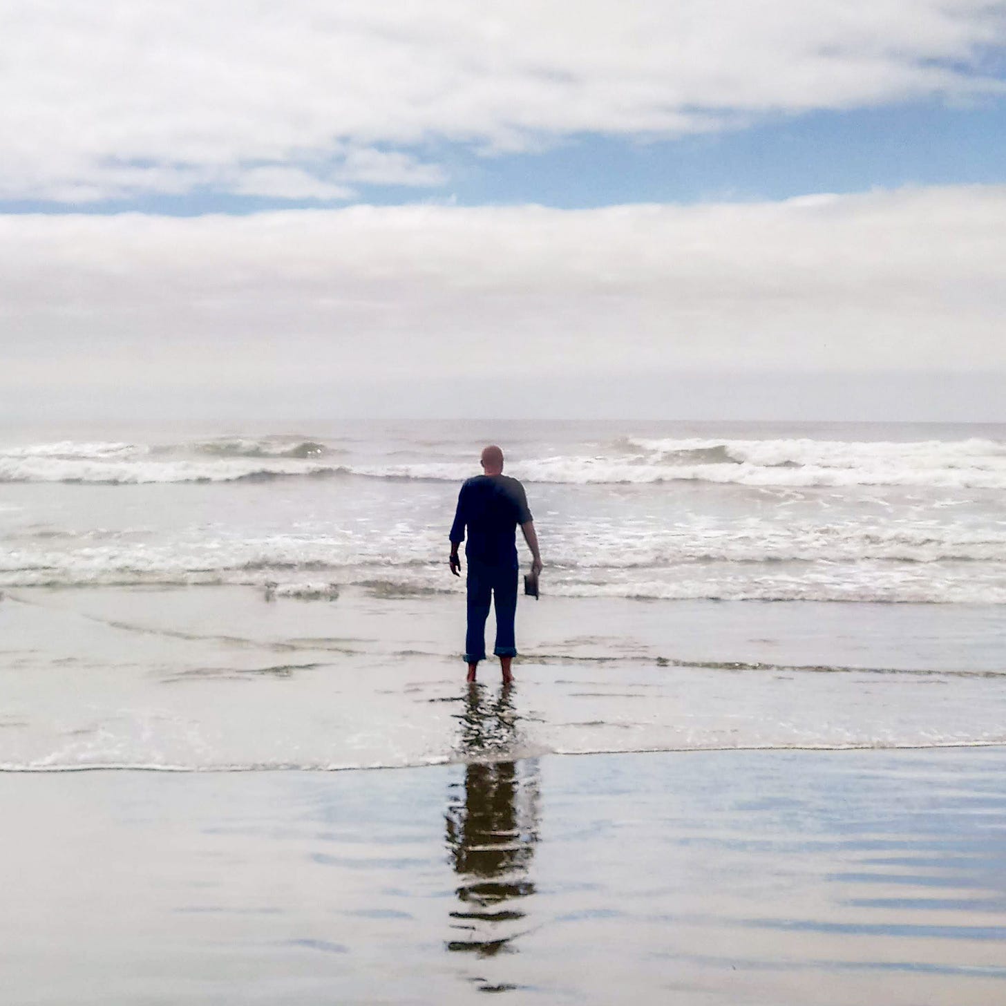 Jeffrey Puukka standing in the surf, looking out at the sea, in article 5 of THOUGHT BUBBLES, by Jeffrey Puukka.
