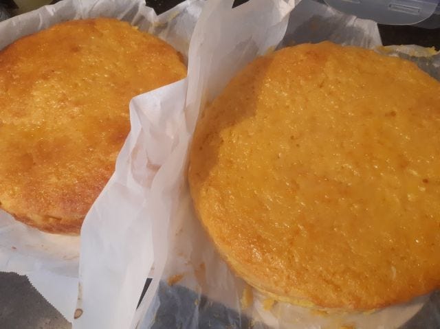 Two freshly baked whole-orange cakes, still in parchment paper.