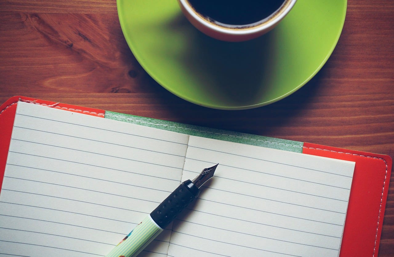 blank notebook with fancy pen and coffee cup