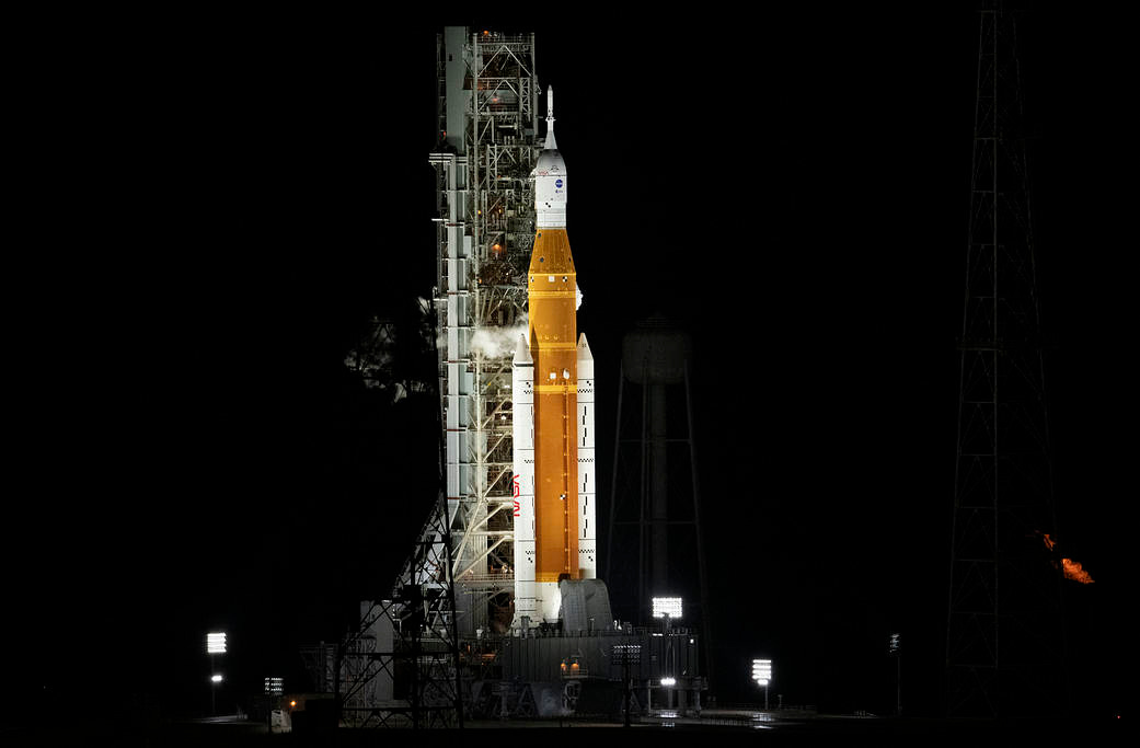 Artemis I sits on the Launch Pad. It is illuminated in the dark.