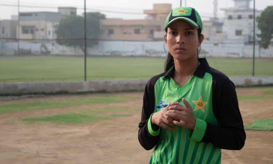 A female player in a Pakistan shirt holds a ball at a cricket ground