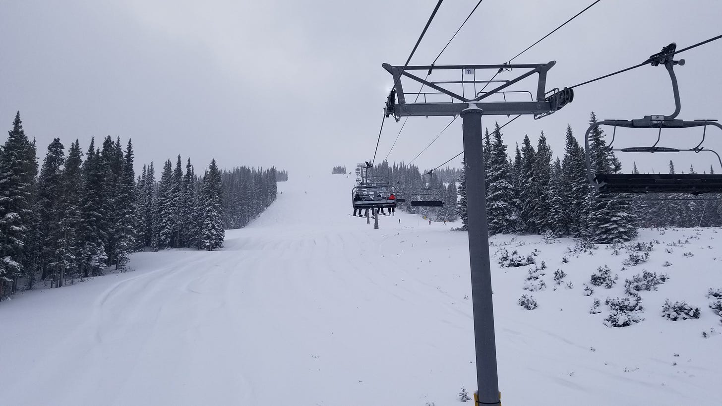 a chairlift over a pristine run on a ski slope. The sky is gray and cloudy.