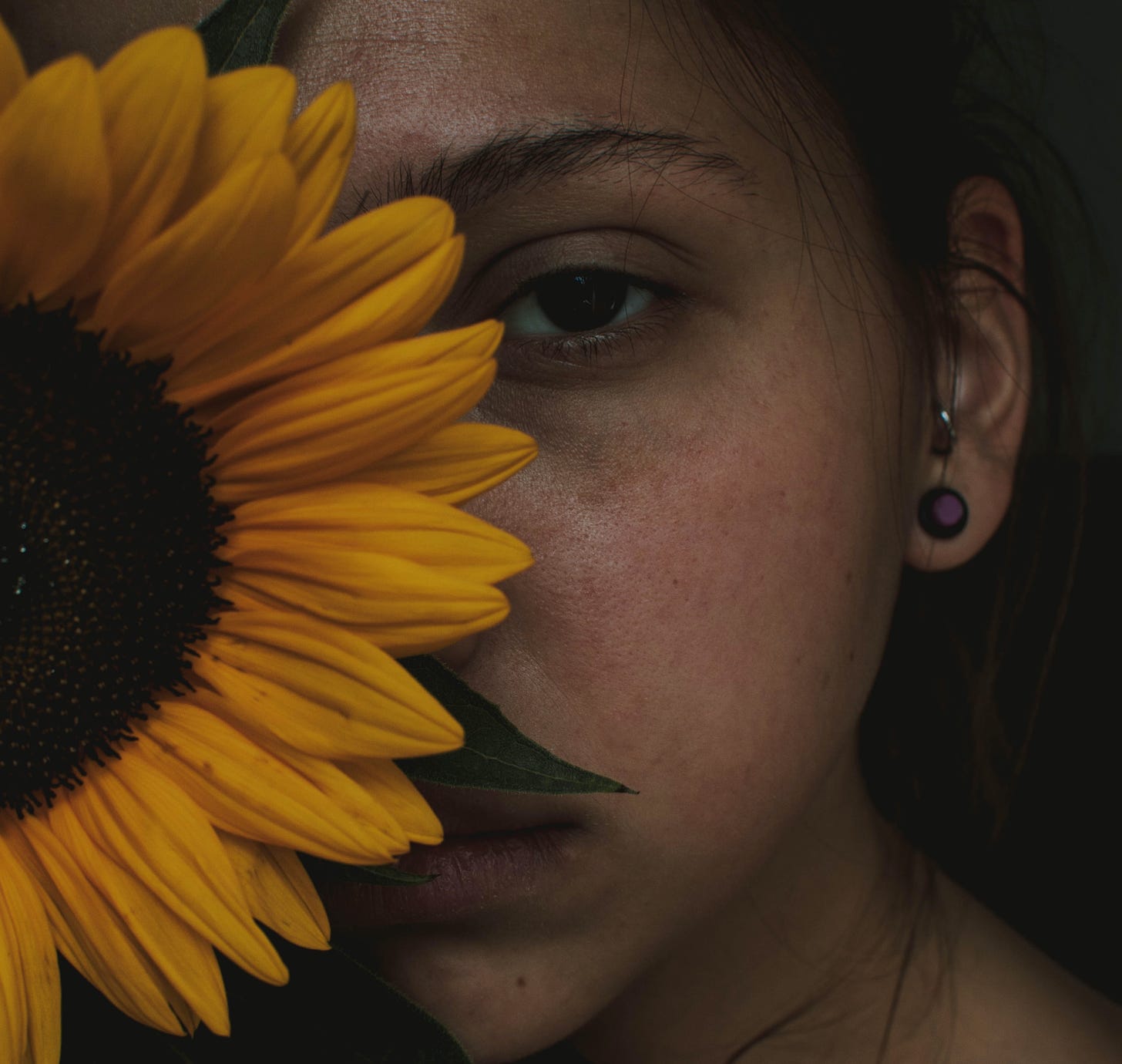 Woman hiding behind sunflower