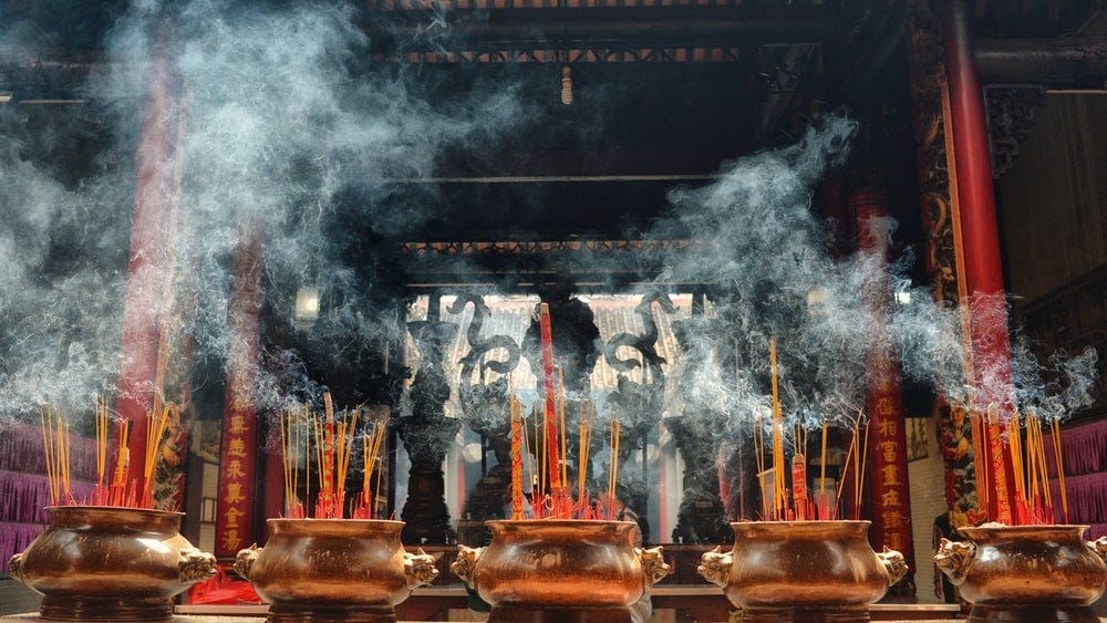 A photograph of a temple in Hanoi, with burning incense on brown vases