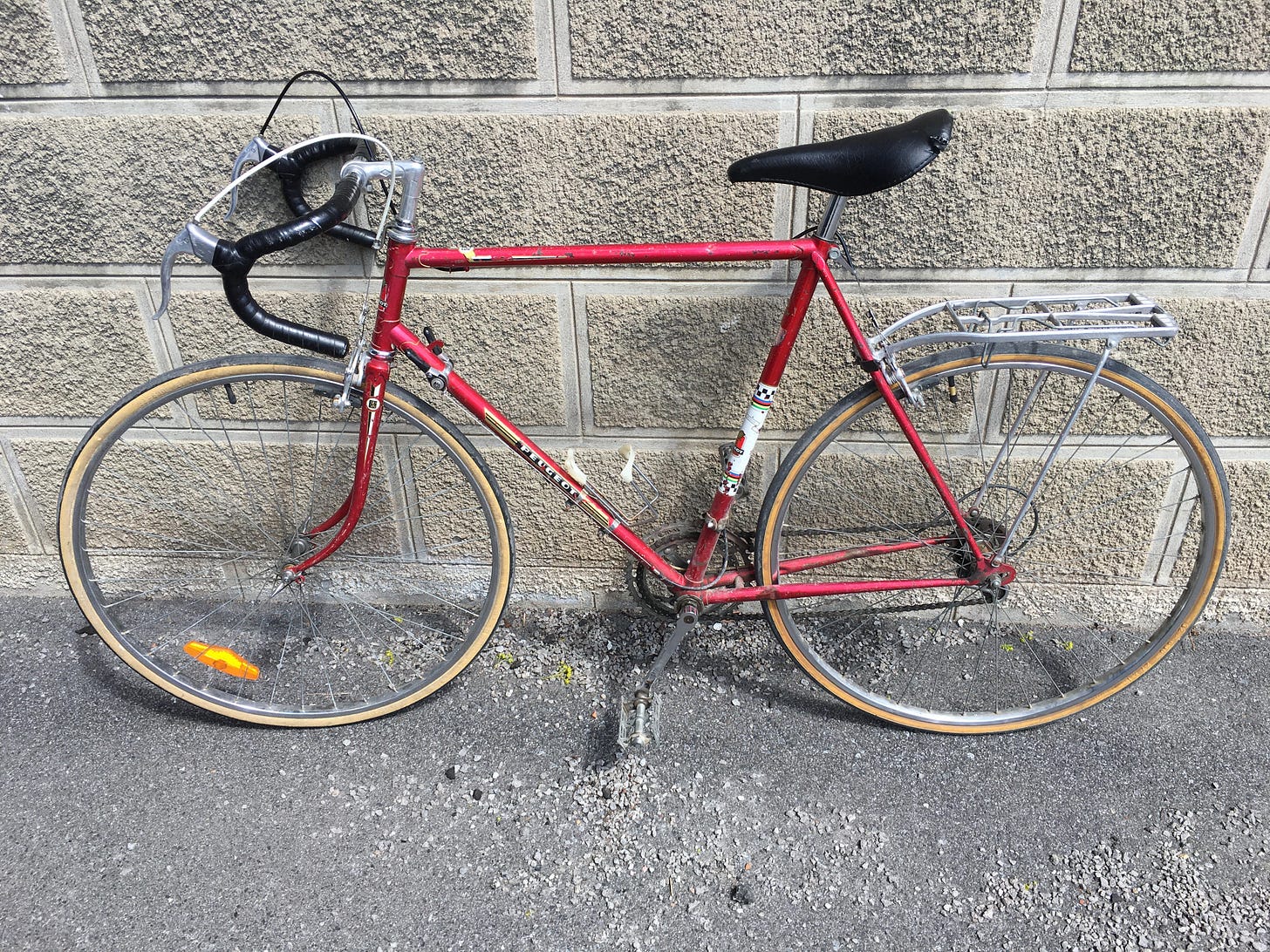 A red 10-speed road bike with drop bars.