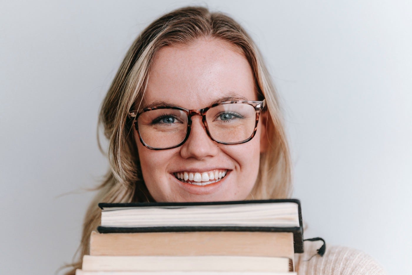 Pretty spectacled woman holding up 3 books