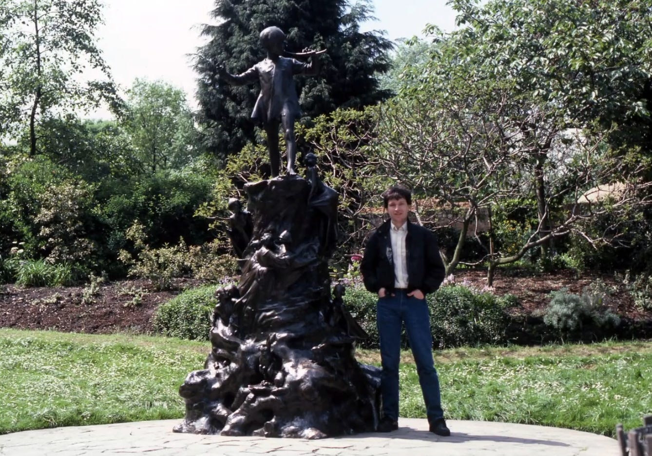 Brian Moriarty standing next to the Peter Pan statue in Kensington Gardens, London.