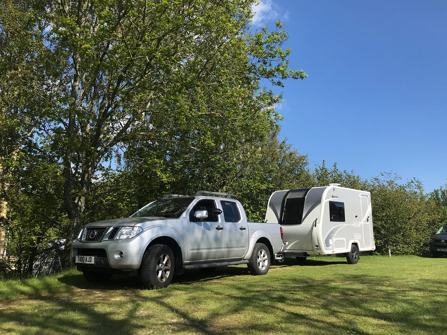 Small caravan on caravan site on a sunny day. Bailey Discovery D4-2 towed by Nissan Navara pick-up. 
