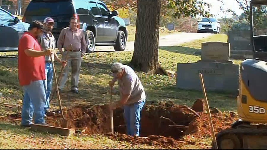 In this photo made from video and released by WSFA-TV, workers labor to exhume the body of a John Doe buried in Alabama in 1981, in Scottsboro, Ala...