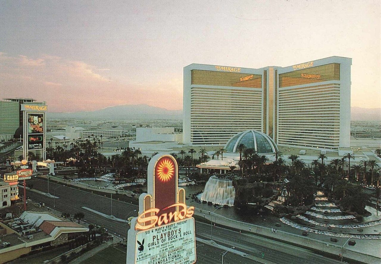 The Mirage – view from the Sands – July 1990. “Playboy’s Girls of Rock & Roll with Sid & Marty Kroff Comedy Kings.” Nob Hill Casino and Denny’s, lower left. (Unknown photographer, postcard.)