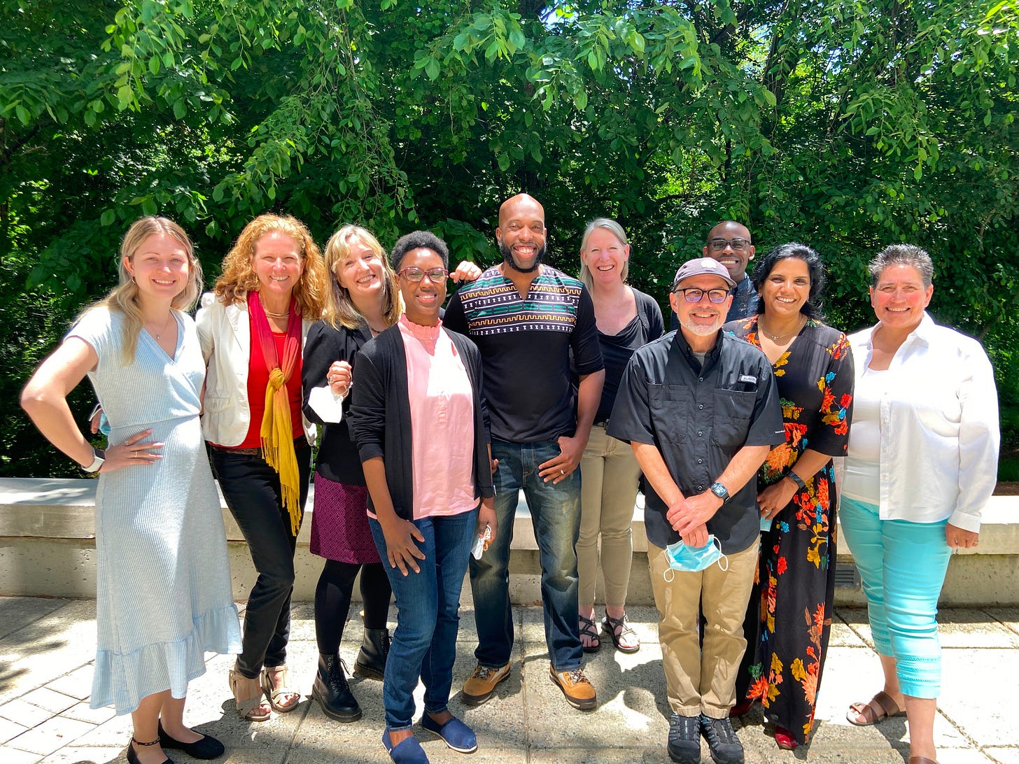 Group of nine amazing educator-scholars smiling outdoors in front of some trees