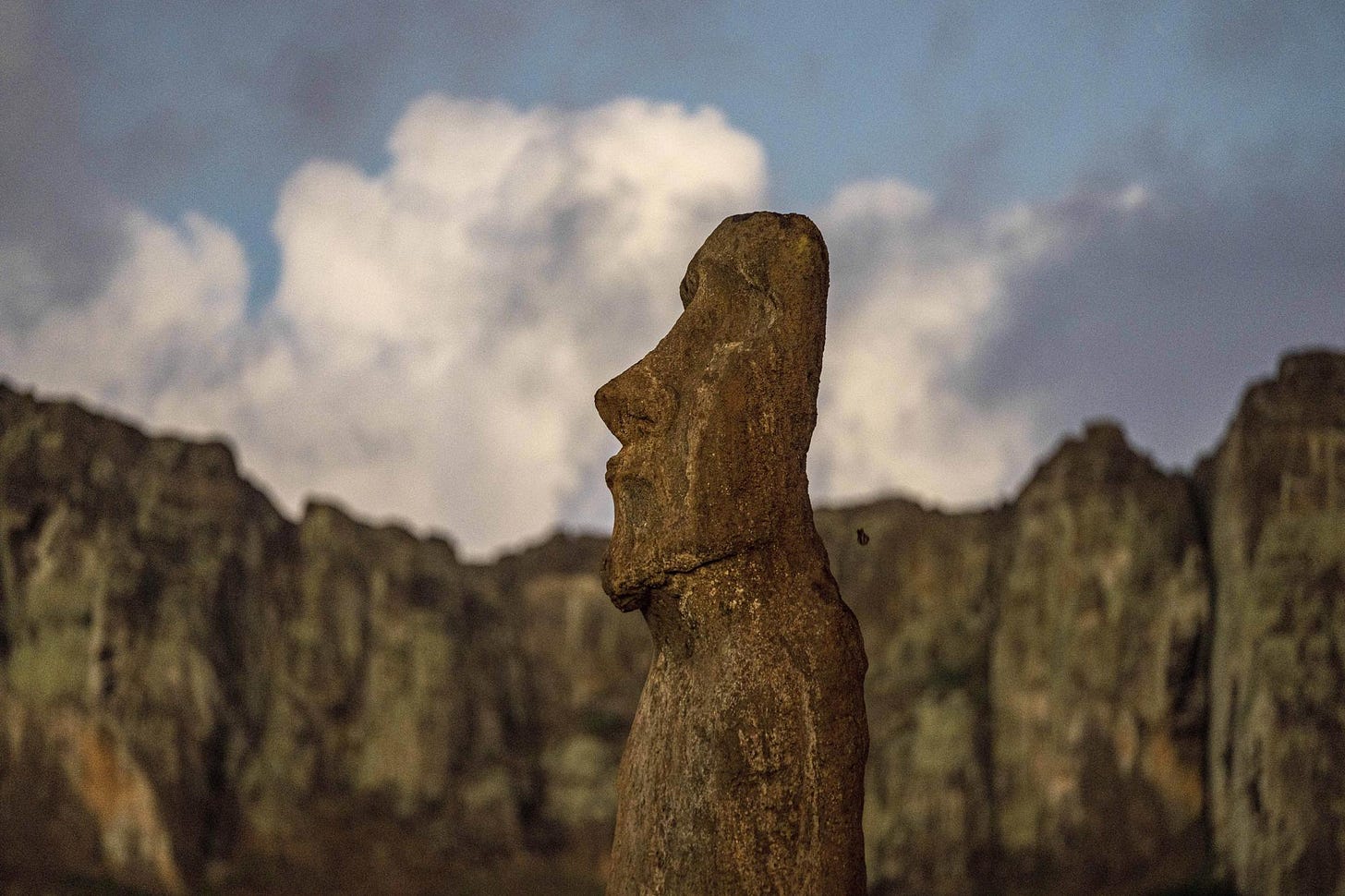 A moai stands behind the Rano Raraku volcano on Ahu Tongariki, Rapa Nui, or Easter Island, Chile, Monday, Nov. 28, 2022. Each monolithic human figure carved centuries ago by this remote Pacific island's Rapanui people represents an ancestor. (AP Photo/Esteban Felix)