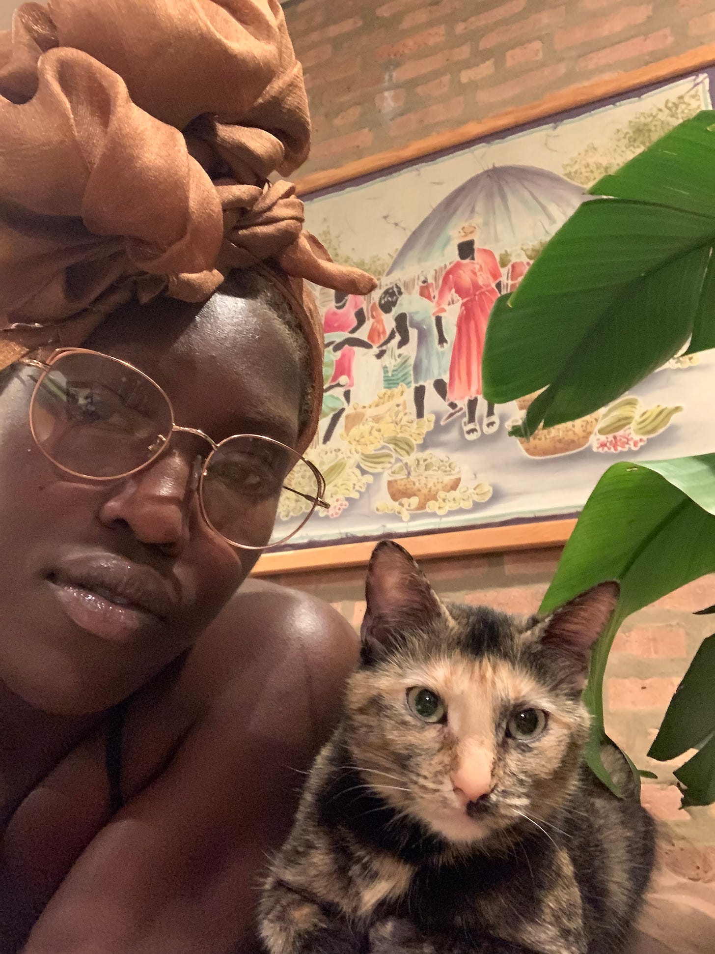 Ismatu in a fluffy golden headscarf pictured with her cat, Lemon