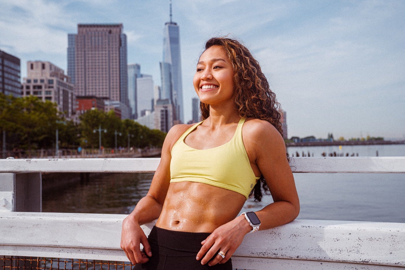 Ripped smiling fit lady in the backdrop of a bridge