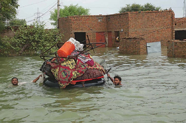 Residents move their belongings from their submerged houses after heavy monsoon rainfall in the Rajanpur district, Punjab, on August 24.— AFP