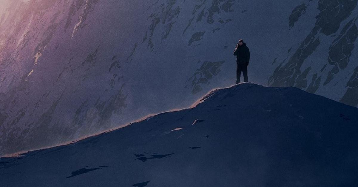A mountaineer on the shadowy ridge of the mountain.