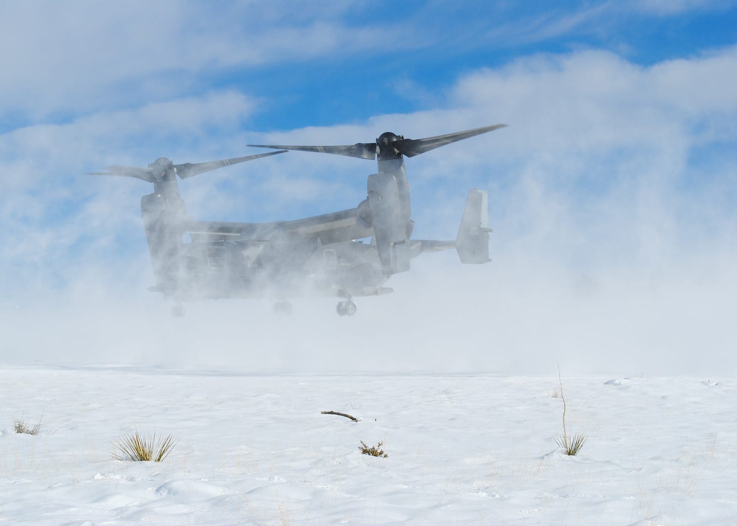 A CV-22 Osprey lands in the snow in the desert