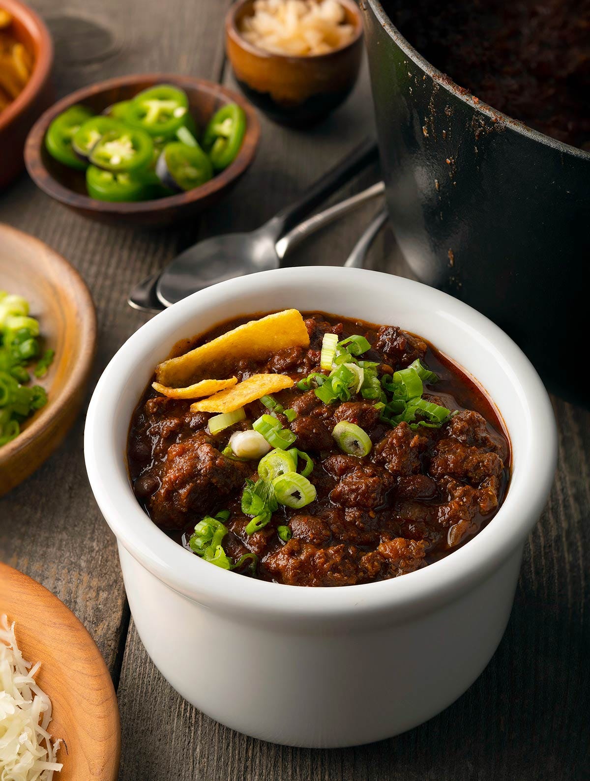A bowl of venison chili, with toppings alongside. 
