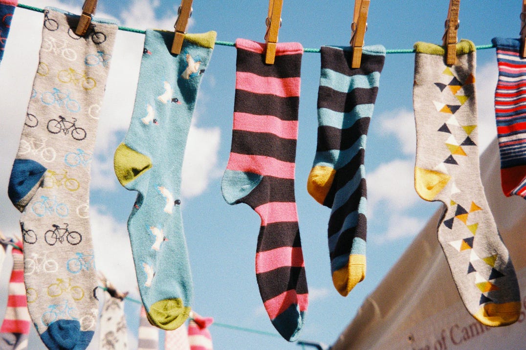 A number of mismatched socks hanging from a line.