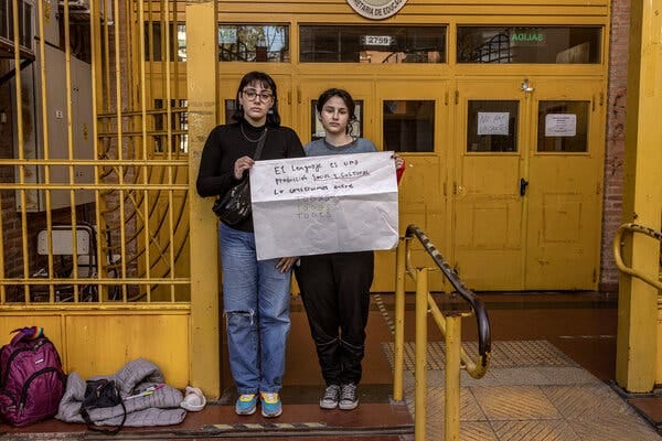 Agostina Fernández Tirra, left, and Luana Pereyra holding a sign using gender-neutral language in front of their school in Buenos Aires.