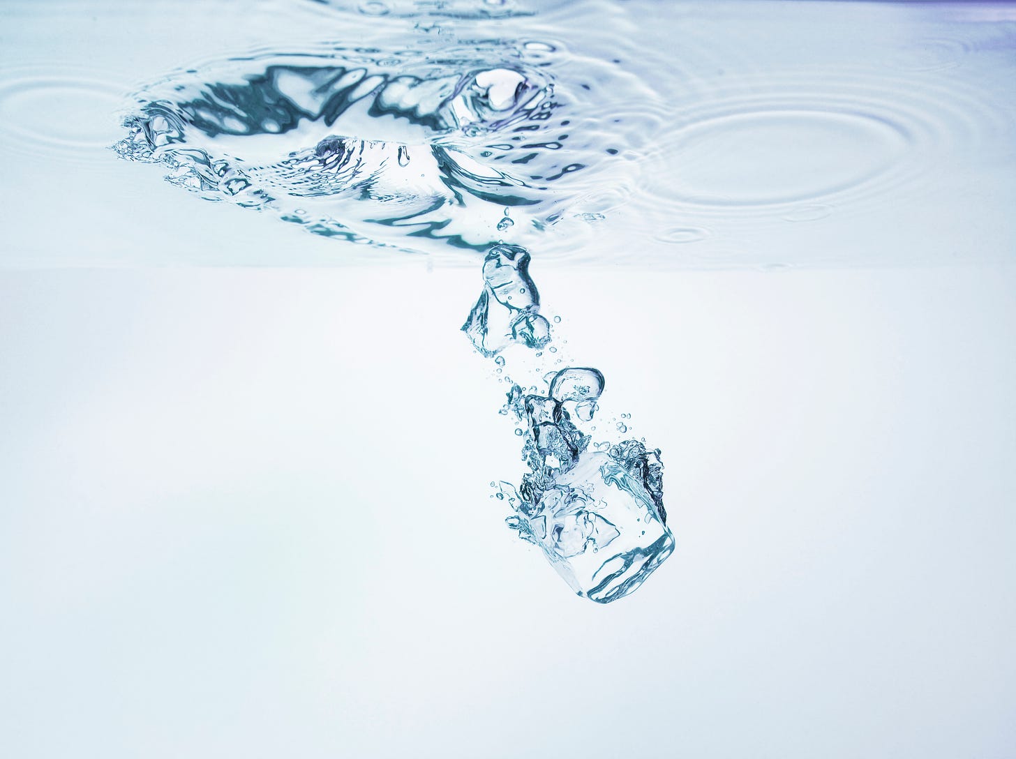 An ice cube falling into clear liquid, probably water