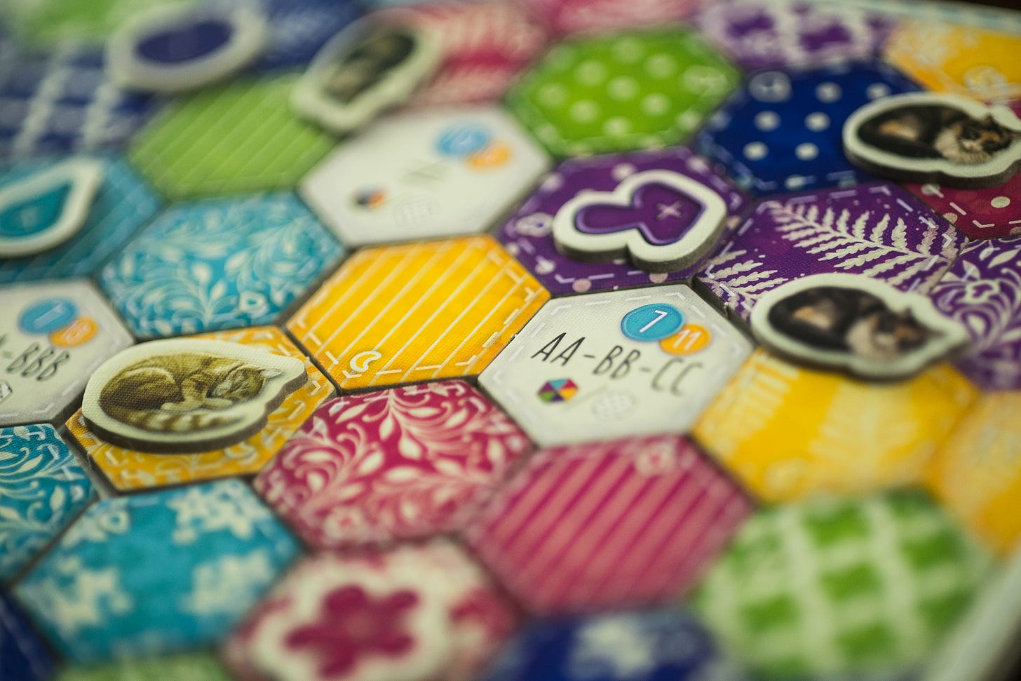 Tiles from the board game Calico placed. There are cat and button tokens on top of the quilt tiles.
